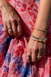 Layered bangles and rings on pink floral dress